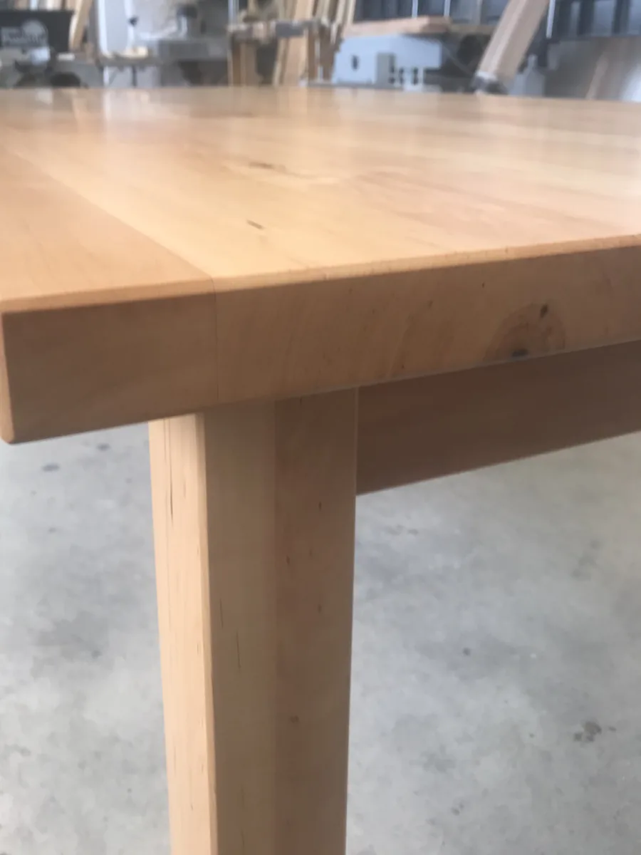 One corner of the top close up: the edge lightly chamfered, the junction of apron and leg beneath it.