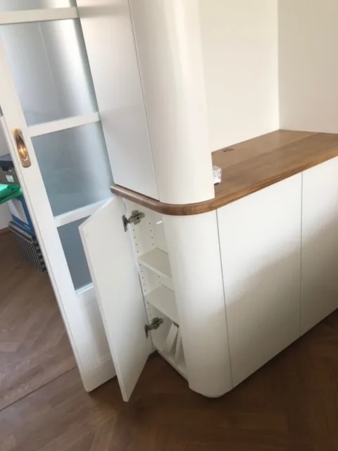 Die gerundete senkrechte Kante der Schrankwand aus Eiche, daneben die Sprossen der Glastür.