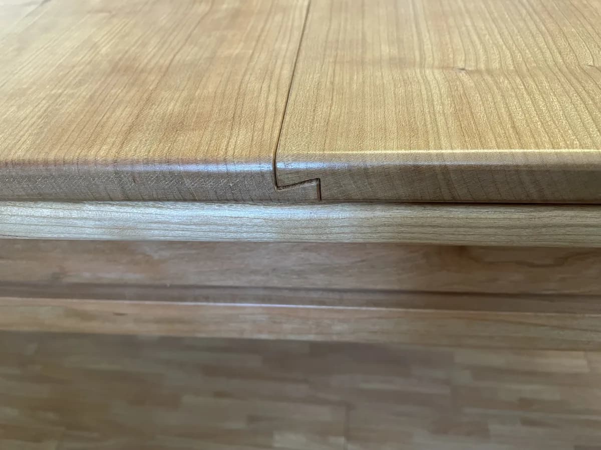 The joint between two panels close up: the panels interlock with a step and rest on the cherry frame.